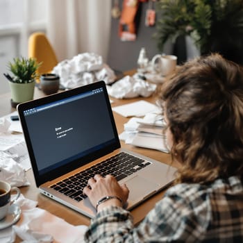 Caucasian young female facing computer error on laptop at cluttered workspace.