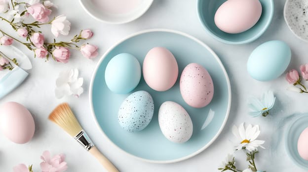 Delicate pastel colored Easter eggs arranged on a blue plate, surrounded by pink blossoms and art supplies.