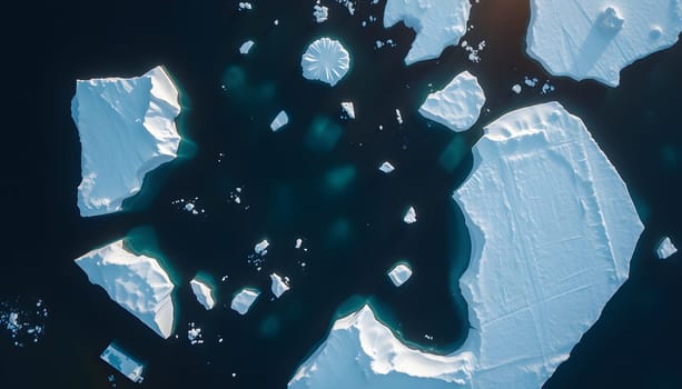 A stunning aerial view of polar icebergs drifting in dark blue waters, with sunlight creating delicate reflections and turquoise hues beneath the ice.