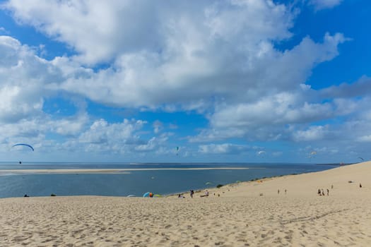 Dune of Pilat, France - August 14, 2024: People paragliding at the Great Dune of Pilat, Arcachon Basin, Nouvelle Aquitaine, France.