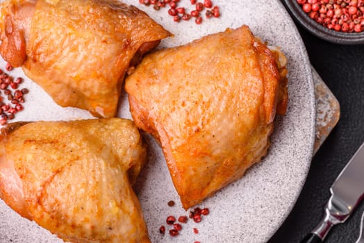 Chicken thighs fried with salt, spices and herbs on a dark concrete background