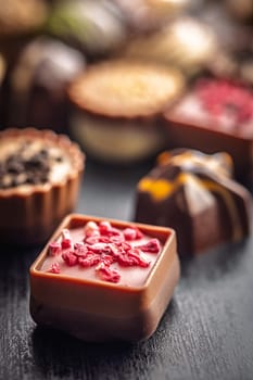 Mix of chocolate pralines on a black table.