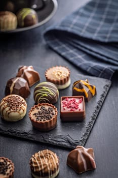 Mix of chocolate pralines on a black table.