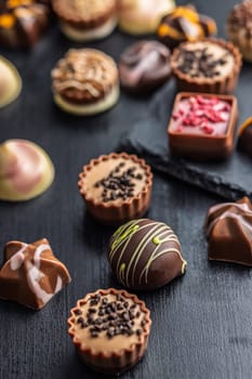 Mix of chocolate pralines on a black table.