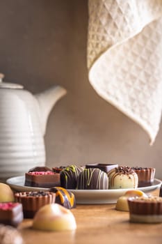 Mix of chocolate pralines on plate on a wooden table.