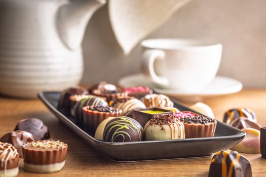 Mix of chocolate pralines on plate on a wooden table.