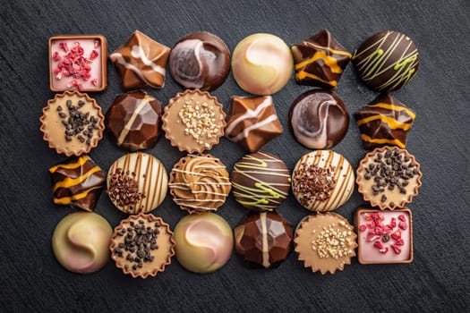 Mix of chocolate pralines on a black table. Top view.