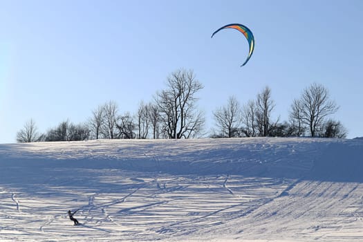 A kitesurfer in winter in the snow. Snowkiting in the mountains