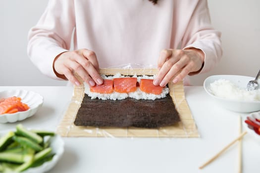 Sushi preparation process, the girl makes sushi with different flavors - fresh salmon, caviar, avocado, cucumber, ginger, rice