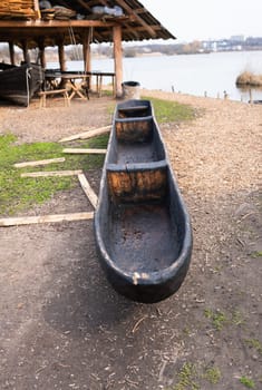 A handcrafted dugout canoe displayed near a lakeside workshop, showcasing traditional wooden craftsmanship.