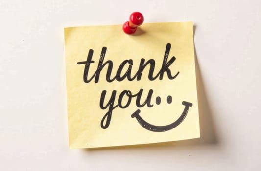 A yellow sticky note with beautifully crafted text expresses gratitude. The note is pinned on a plain background, enhancing its cheerful message and inviting demeanor.
