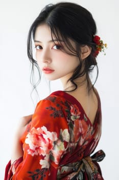 Studio portrait of a young beautiful Asian woman wearing red kimono dress with floral ornament on white background.