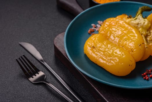 Yellow sweet pepper cut in half and grilled with salt, spices and herbs on a dark concrete background