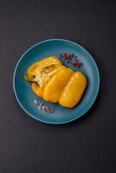 Yellow sweet pepper cut in half and grilled with salt, spices and herbs on a dark concrete background