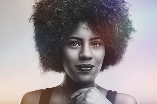 Black and white portrait capturing a beautiful young woman with afro hair, exuding confidence and serenity while gazing directly at the camera with a calm and peaceful expression
