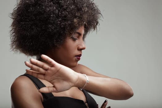 Studio portrait of a young latin american woman with curly hair making a stop sign with her hand, expressing a clear message of refusal or setting boundaries