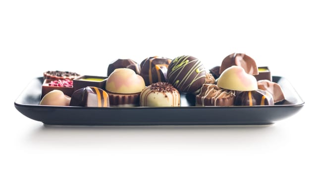 Mix of chocolate pralines on plate isolated on a white background.