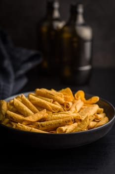 Rolled nachos tortilla chips on plate on a black table.