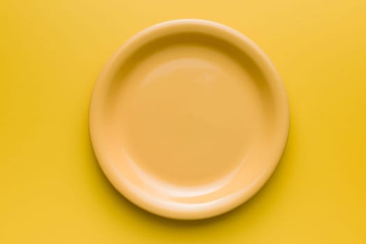 Empty yellow plate on an yellow background. Top view.