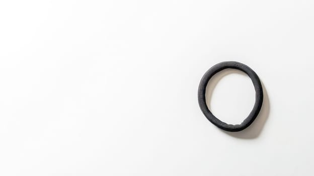 Plain black hair tie rests on a minimalist light background, creating a striking contrast and offering a clean, simple aesthetic perfect for beauty, fashion, or lifestyle projects