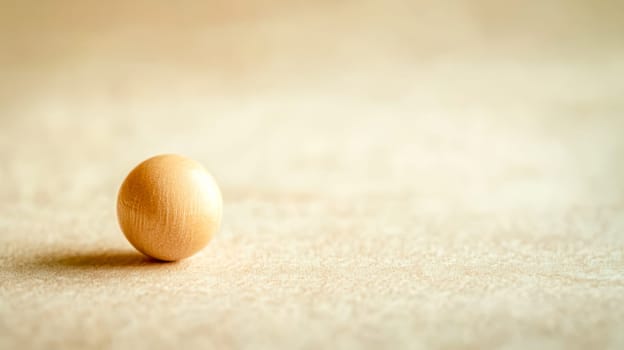Small, smooth, light brown wooden bead resting on a light beige, textured background, creating a simple yet elegant composition with copy space