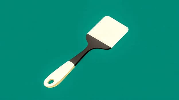 Kitchen spatula with beige handle and dark gray blade resting on a vibrant teal backdrop, presenting a minimalist and modern culinary aesthetic
