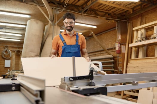 Male artisan worker holding and assembling pieces of wood using glue working at workbench. Craftsmanship and carpentry studio concept