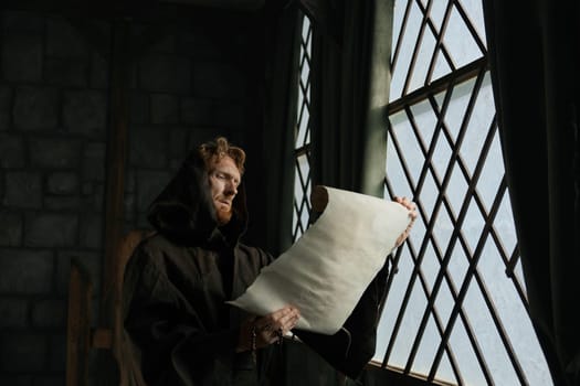 Medieval monk reading obsolete historical parchments and holy manuscripts. Abbey chronicler preparing monastic archive