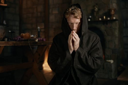 Medieval monk wearing robe wishing and praying to God looking upward in mediaeval monastery