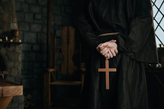 Closeup view cropped shot with golden cross in priest monk hands. Medieval friar praying concept