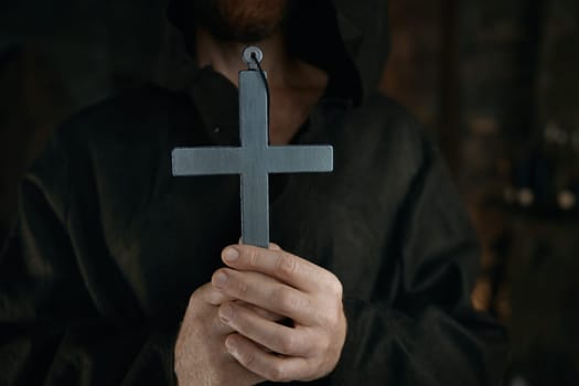 Silver cross in medieval monk hands. Historic priest in monastery