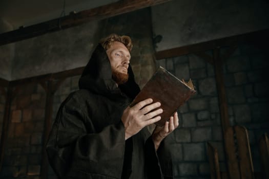 Thoughtful medieval monk reading ancient book or antique manuscripts in cathedral. Religion and faith concept