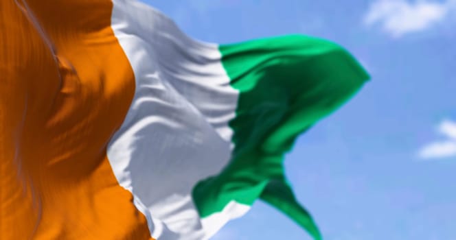 Ivory Coast national flag waving in the wind on a clear day. Three equal vertical stripes: orange, white, and green. 3d illustration render. Fluttering fabric
