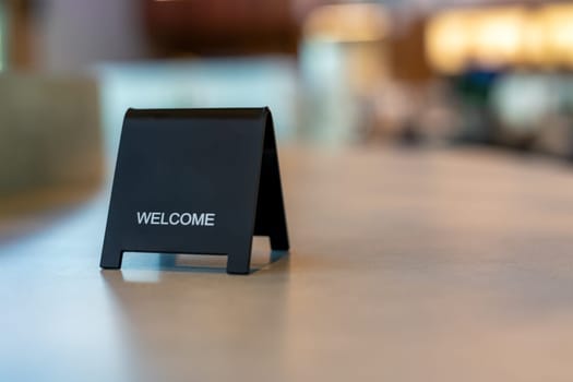 Black sign there is a message saying Welcome with a copy space is placed on a cement table for Enter the text of restaurant, store, or cafe.