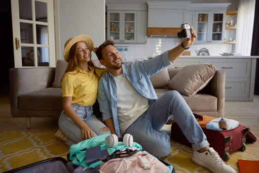 Happy loving couple taking photo using vintage camera during preparation for summer vacation at tropical resort