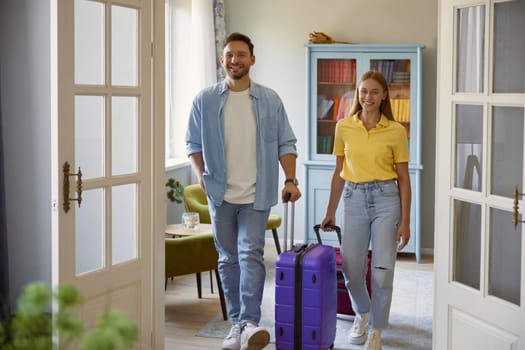 Young man and woman couple leaving home with packed travel suitcase. Starting vacation season concept