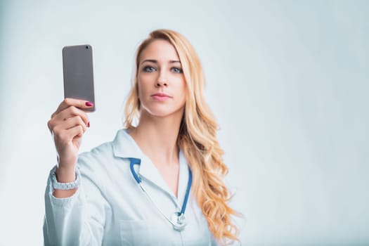 Young female doctor using a smartphone app for remote patient monitoring and ai-powered diagnostics, revolutionizing healthcare with technology
