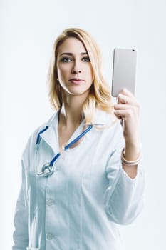 Young female doctor wearing a lab coat and stethoscope is holding a smartphone in front of her, showcasing the potential of artificial intelligence and automation in the medical field