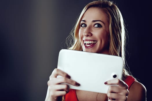 Excited young woman with long blond hair and a red dress smiles while holding a digital tablet, possibly using ai-powered apps or exploring the possibilities of artificial intelligence