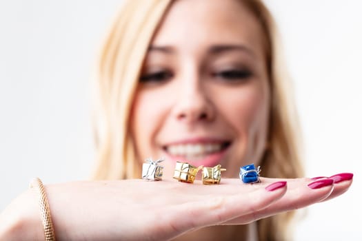 Four tiny gift boxes on a young woman's hand, in focus, with a blurred satisfied and smiling face in the background. Giving is as joyful as receiving