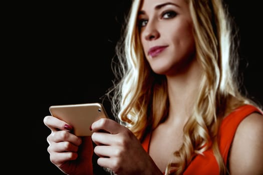 Young woman with blond hair and an elegant red dress is using a smartphone, possibly interacting with artificial intelligence and automation, pondering the impact on her life and future