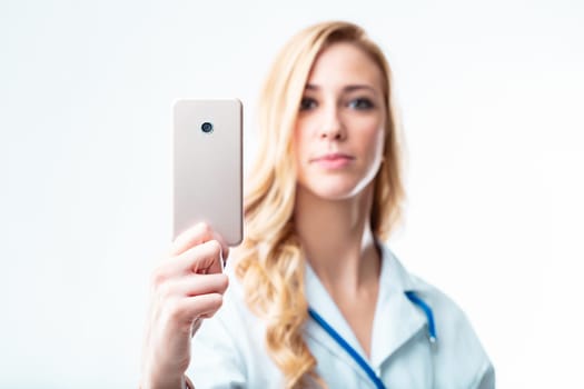 Young female doctor blurred behind an in-focus smartphone, reminding of the usefulness of telehealth and medical apps