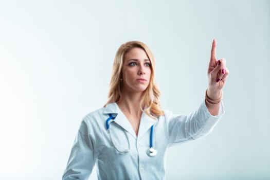 Blurred female doctor, blonde in white coat, gestures to place your floating graphic. A scientist in high-tech hospital setting
