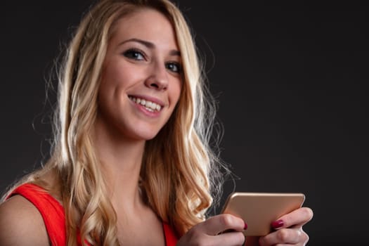 A blurred, smiling face of a young woman holding a sharply focused smartphone. It embodies online work, shopping, communication, gaming, and online dating