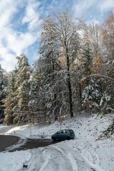 Car parked in a forest parking lot with lots of snow and blue sky