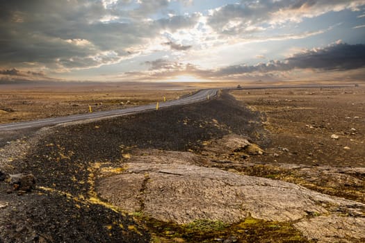 Asphalt road volcanic landscape in iceland under cloudy sky during sunset