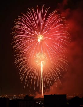Brilliant red and gold fireworks explode against the dark sky, reflecting in the waterway. The celebration lights up the city skyline during a festive nighttime event. Generative AI.