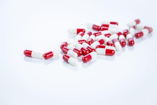 Red and white capsule pills spread on white background. Prescription drugs, pharmaceutical innovation, healthcare solutions. Medicine in modern clinical treatments. Precision drug development.