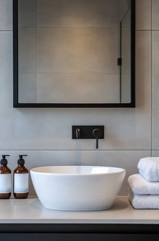 A sleek bathroom features a white bowl sink with simple fixtures and neatly stacked towels, creating a calm and clean aesthetic.