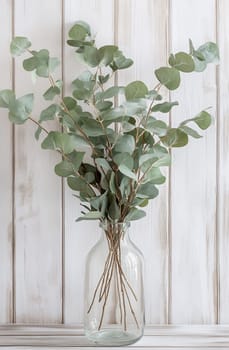 Fresh eucalyptus stems are beautifully arranged in a clear glass vase against a rustic wooden background, creating a calming atmosphere.